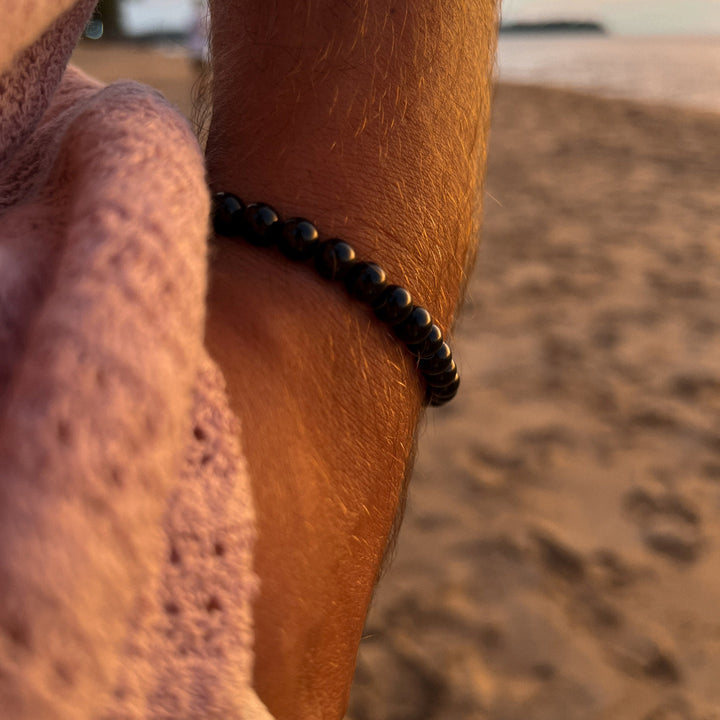 Maennliches_Model_traegt_Schwarzes_Perlenarmband_aus_6mm_glaenzenden_Onyx_Edelstein_Perlen_mit_Makramee_Verschluss_von_DeinSchmuck_by_TL